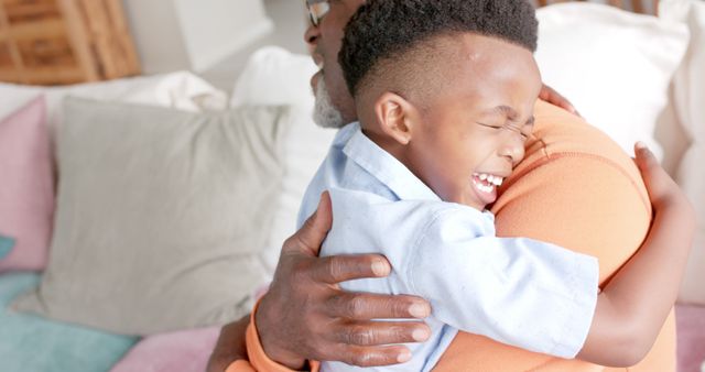 Happy african american grandfather and grandson hugging at home. Lifestyle, childhood, free time, family, togetherness and domestic life, unaltered.