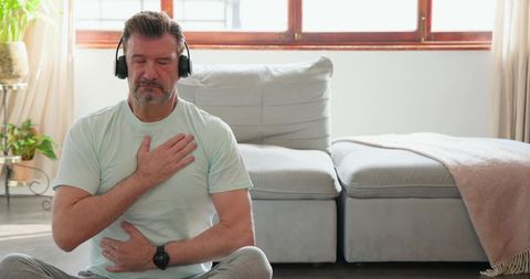 Mature Man Meditating with Headphones at Home for Relaxation