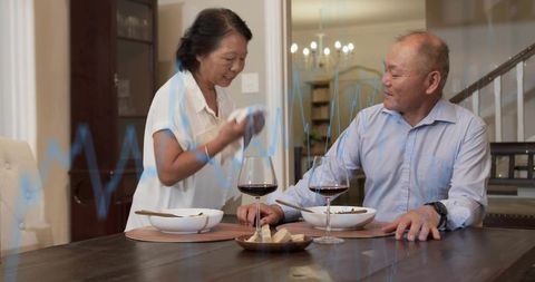 Mature couple enjoying relaxed dinner at home with wine and warm dining room ambience