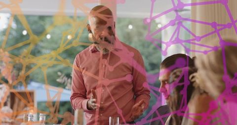 Bald man speaking at casual dinner meeting with digital network overlay
