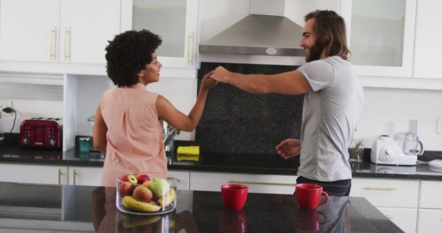 This image shows a happy couple laughing and enjoying their morning coffee in a modern kitchen equipped with various appliances. They seem to share a friendly interaction, symbolizing a healthy and joyful relationship. Use this image for lifestyle blogs, cooking websites, or advertisements emphasizing modern home life, morning routines, or relationship dynamics.