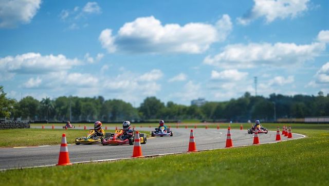 Go-kart racers navigating track with orange cones under blue sky