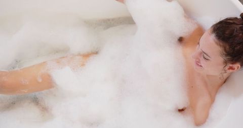 Woman Relaxing in Bathtub Covered with Foamy Bubbles