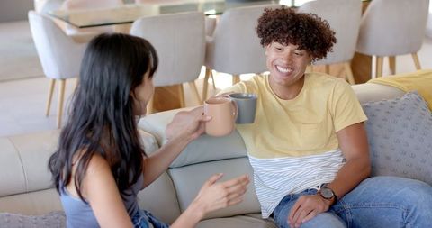 Diverse Friends Relaxing Together Clinking Coffee Mugs on Comfortable Sofa