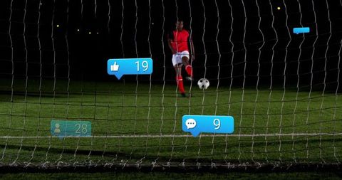 Red Uniformed Soccer Player Kicking Ball at Night on Grass Field