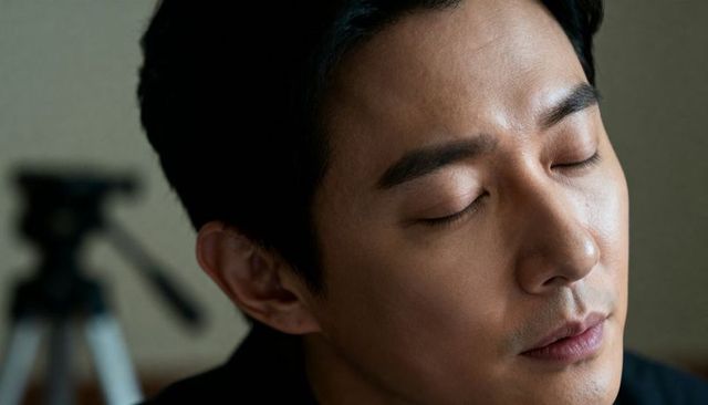 Resting asian man keeping eyes closed in calm closeup portrait with soft bokeh backdrop