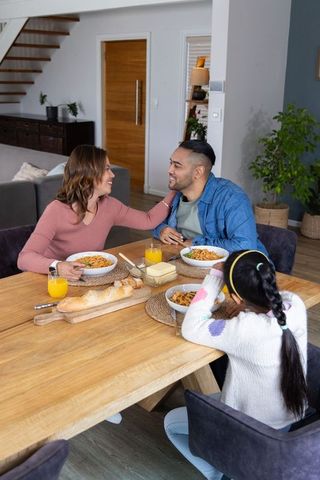 Family sharing spaghetti around wooden table showing warmth, connection, everyday joy