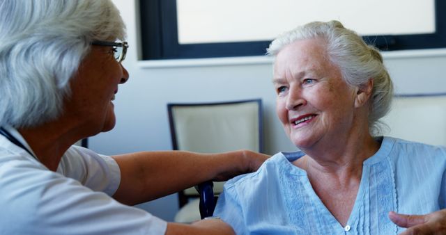 A senior Caucasian woman is being cared for by a healthcare professional, a nurse or doctor, with copy space. Their interaction suggests a compassionate medical consultation or a routine health check-up.