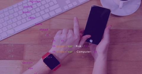 Developer tapping smartphone with red smartwatch on wooden desk showing code overlay