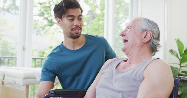 Young Caregiver Interacting with Elderly Man in Wheelchair in Bright Room - Download Free Stock Images Pikwizard.com