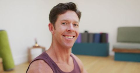 Smiling Man in Lotus Position in Modern Yoga Studio