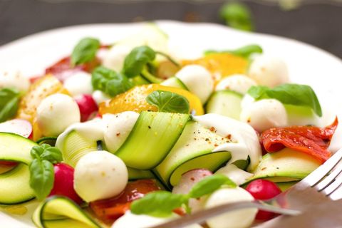 Fresh zucchini ribbon caprese salad with mozzarella pearls, roasted tomatoes and basil