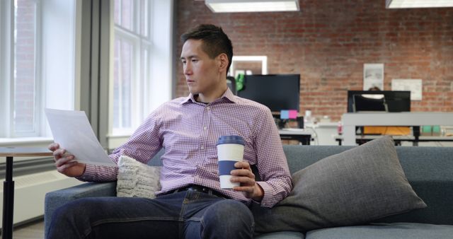 Young Professional Reviewing Document While Relaxing in Office - Download Free Stock Images Pikwizard.com