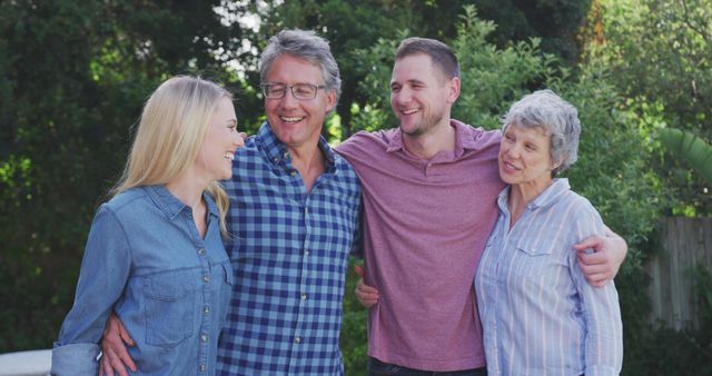 Group of four family members standing outside in lush garden, smiling and embracing. Great for family or lifestyle content, marketing materials centered on togetherness, ads promoting family activities, or blogs about multigenerational relationships.