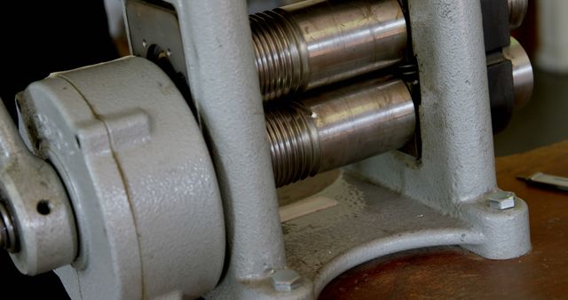 Close-up view of a metal roller mechanism, part of an industrial machine, with focus on the threaded rollers. The image captures the intricate details of the machinery, emphasizing the precision required in industrial equipment design.