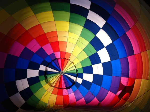 Bright and vibrant interior view of a hot air balloon canopy seen from below, showing a geometric, colorful pattern. Ideal for travel promotion, adventure tourism, festival events, and advertisements seeking attention-grabbing visuals and vibrant marketing materials.