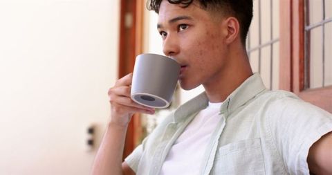 Young Man Relaxing Indoors with Coffee Mug, Contemplating