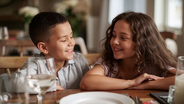 Smiling preteen boy and girl sharing warm conversation at family dinner table