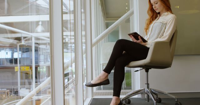 Young Professional Sitting in Modern Office Hallway Using Tablet - Download Free Stock Images Pikwizard.com