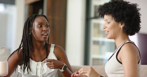 Two african american women enjoying casual conversation in sunlit living room