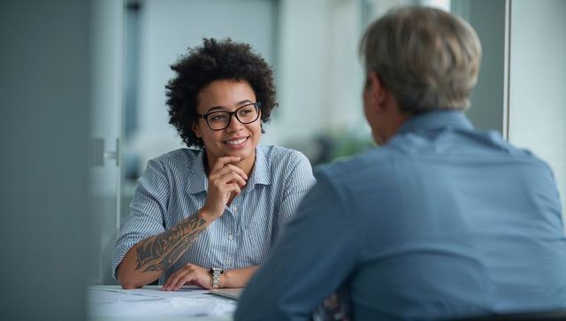 Engaged young professional with arm tattoo and glasses during friendly office interview