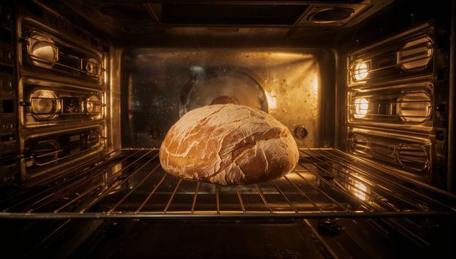 Artisan bread loaf baking in illuminated kitchen oven