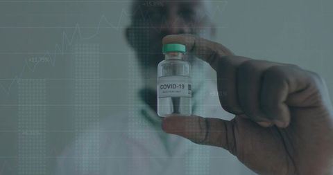 Doctor Analyzing COVID-19 Vaccine Data with Vial in Focus