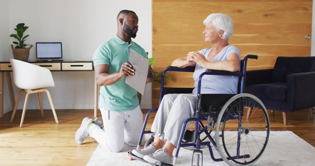 Image of happy african american male physiotherapist examining caucasian senior woman on wheelchair. o seniors health and nursing home lifestyle concept.