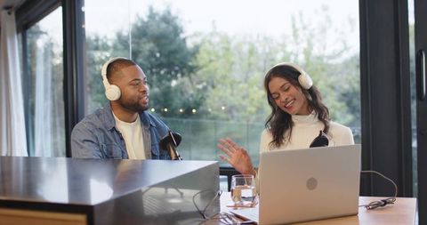 Recording casual home podcast with diverse co-hosts using laptop, microphones, headphones