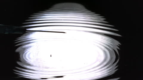 Water Droplet Rippling on Dark Surface Shot in Slow Motion