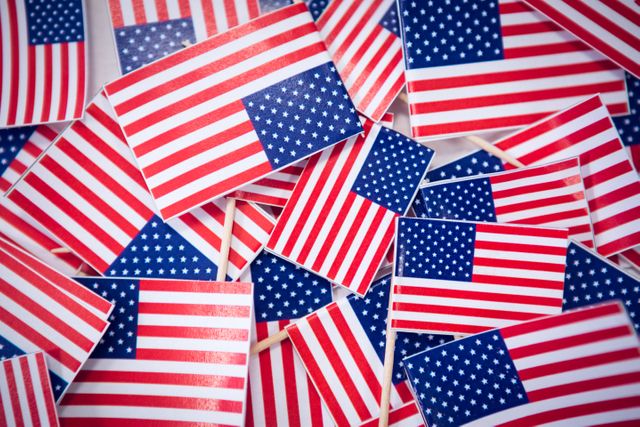 This image shows a collection of small American national flags viewed from above. Ideal for use in patriotic events, national holidays like Independence Day, Memorial Day, and Veterans Day, or any content celebrating American culture and pride. Perfect for websites, social media posts, and promotional materials.