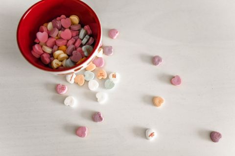 Assorted heart-shaped candies spilled from red bowl