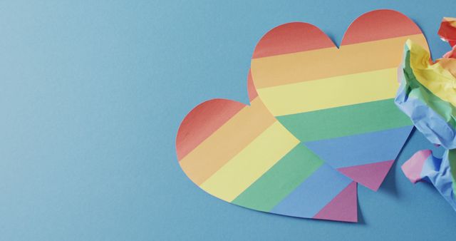 Image of rainbow hearts over blue background with copy space. Gender, lgbt, queer, gay pride and equality concept.