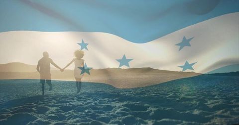 Couple running on beach with translucent flag at sunset