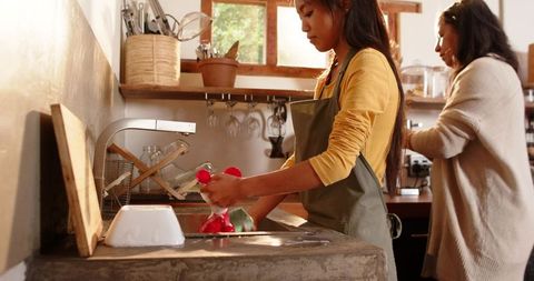 Mother and Daughter Cleaning Dishes in Rustic Kitchen
