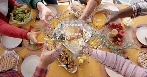 Friends Toasting with Orange Juice at Holiday Table with Holographic Globe