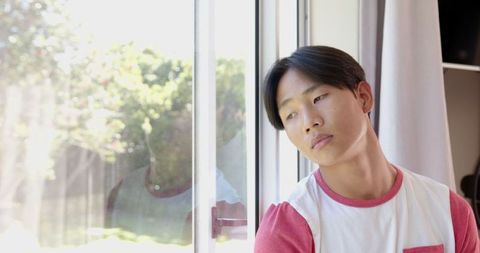 Teenage Boy Contemplation by Sunlit Glass Door at Home