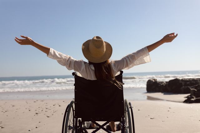 Rear view of disabled woman with arms outstretched on the beach