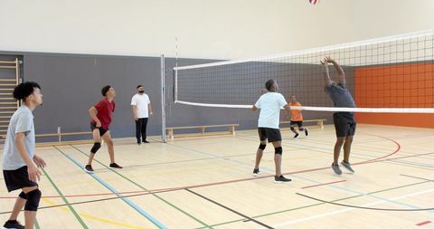 African american man jumping and blocking volleyball at net in indoor gym