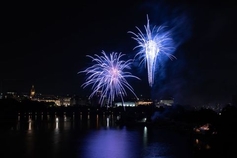 Spectacular Blue Fireworks Over Cityscape Reflected in Calm River