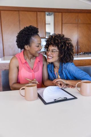 Midlife couple signing contract at kitchen counter, sharing laughter and holding hands