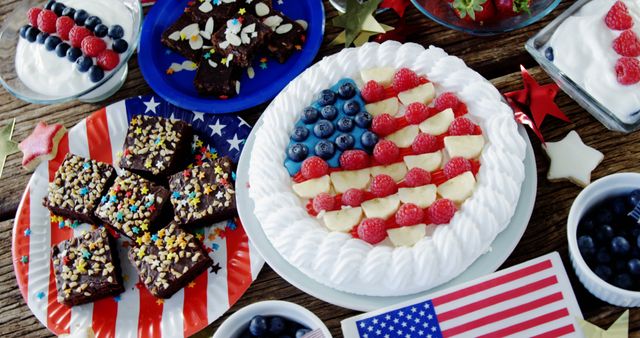 Patriotic dessert spread featuring American flag-themed desserts, including a cake decorated with raspberries and blueberries, fruit desserts, and brownies with colorful sprinkles. Perfect for Independence Day, Memorial Day, or any American holiday celebration. Ideal for party planning inspiration, festive gatherings, and food blogs featuring holiday treats.
