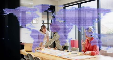 Women collaborating over project plans with holographic world map in bright boardroom
