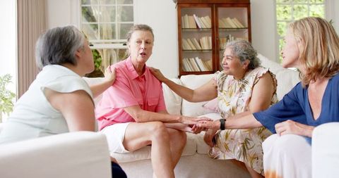 Senior friends comforting each other in cozy living room setting