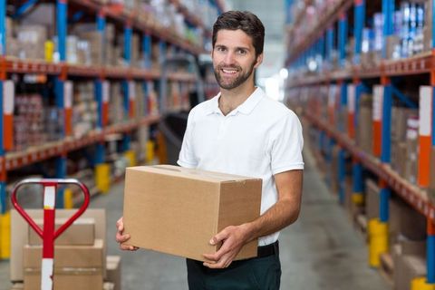 Warehouse worker holding cardboard box in industrial storage aisle