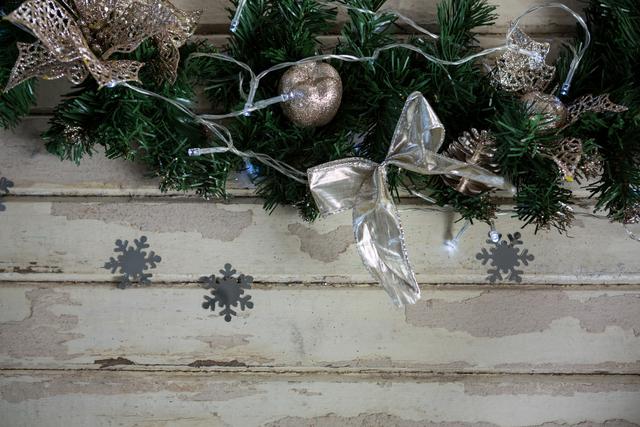 Christmas garland adorned with gold ornaments, ribbons, and snowflakes on rustic wooden background. Ideal for holiday greeting cards, festive invitations, seasonal advertisements, and Christmas-themed blog posts.