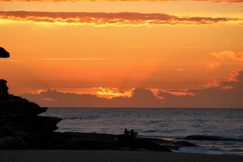 Dramatic Sunset over Ocean Silhouetting People on Rocks