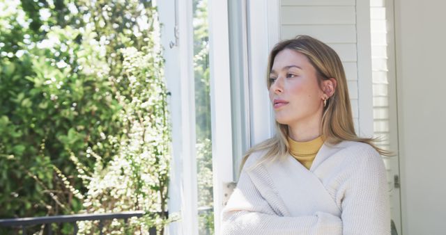 Pensive Woman Gazing Through Window in Sunlit Home - Download Free Stock Images Pikwizard.com