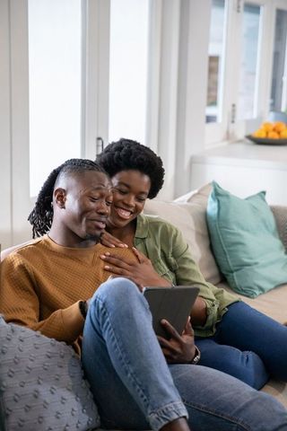 Couple Relaxing on Sofa at Home with Tablet