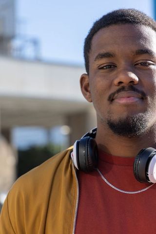 African american man standing wearing headphones at urban overpass, casual portrait